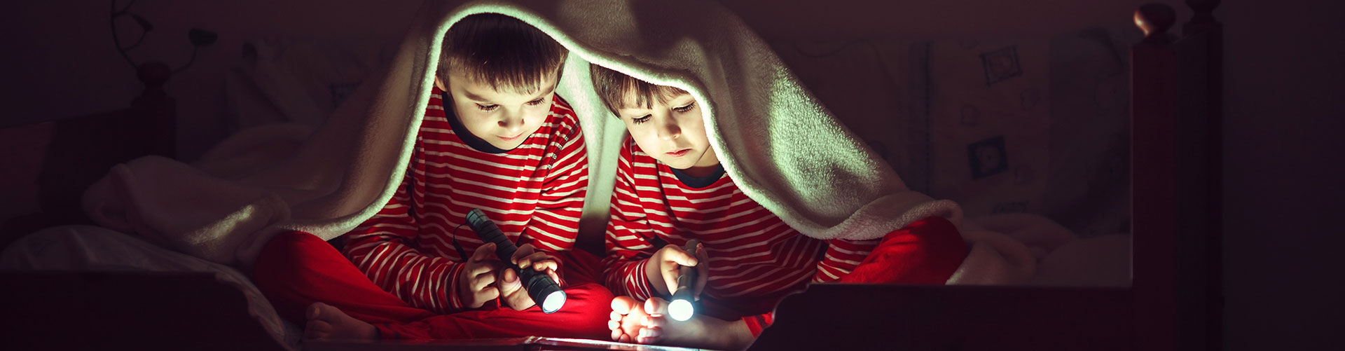 kids under blanket with flashlight